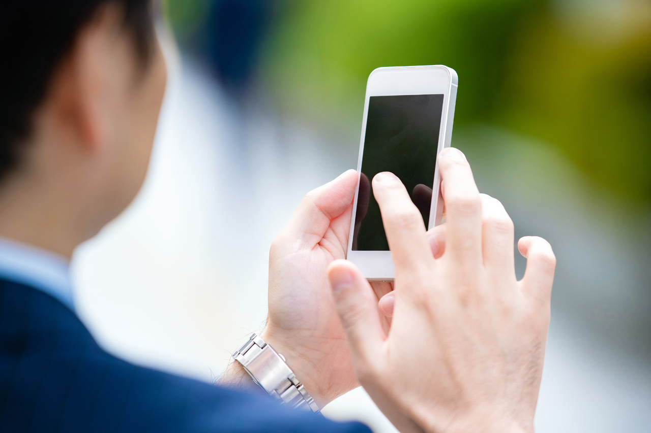 屋外でスマホを操作する